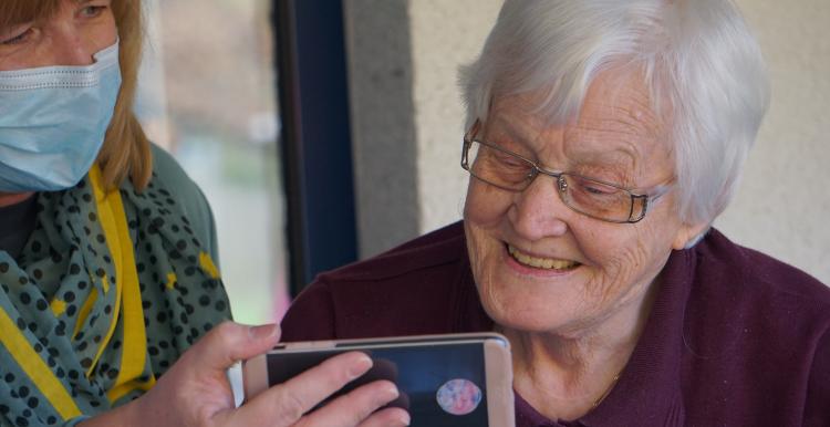 Woman holding a mobile phone for an elderly woman