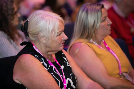 Two women sitting in a row watching something off camera